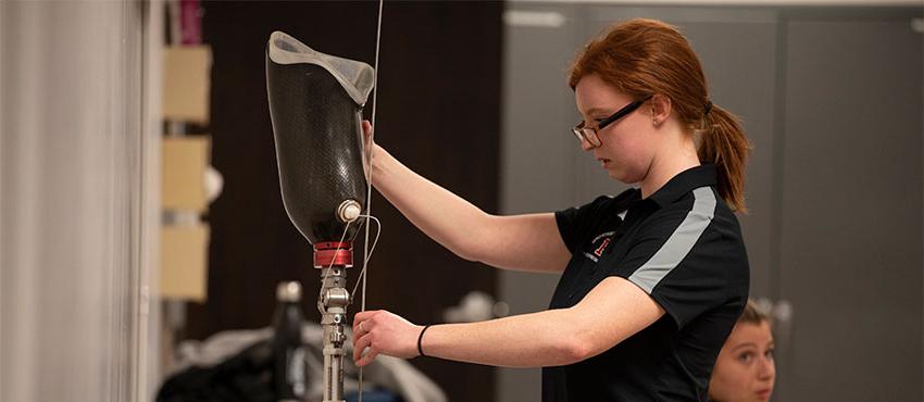 Student examining prosthetic leg